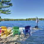 Muskoka chairs clustered at shore for view of Severn River